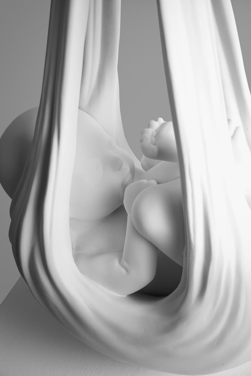 Babydrone by Federico Clapis, close-up of the white resin infant curled up asleep inside the folds of the fabric sling