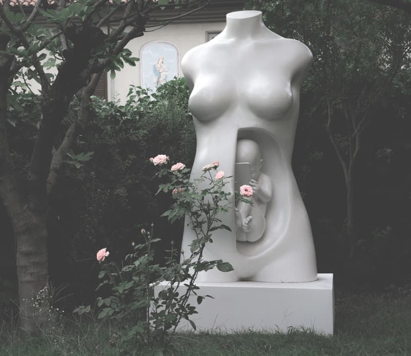 Connection by Federico Clapis: large white resin female torso in a garden, a fetus holding a smartphone visible inside its womb