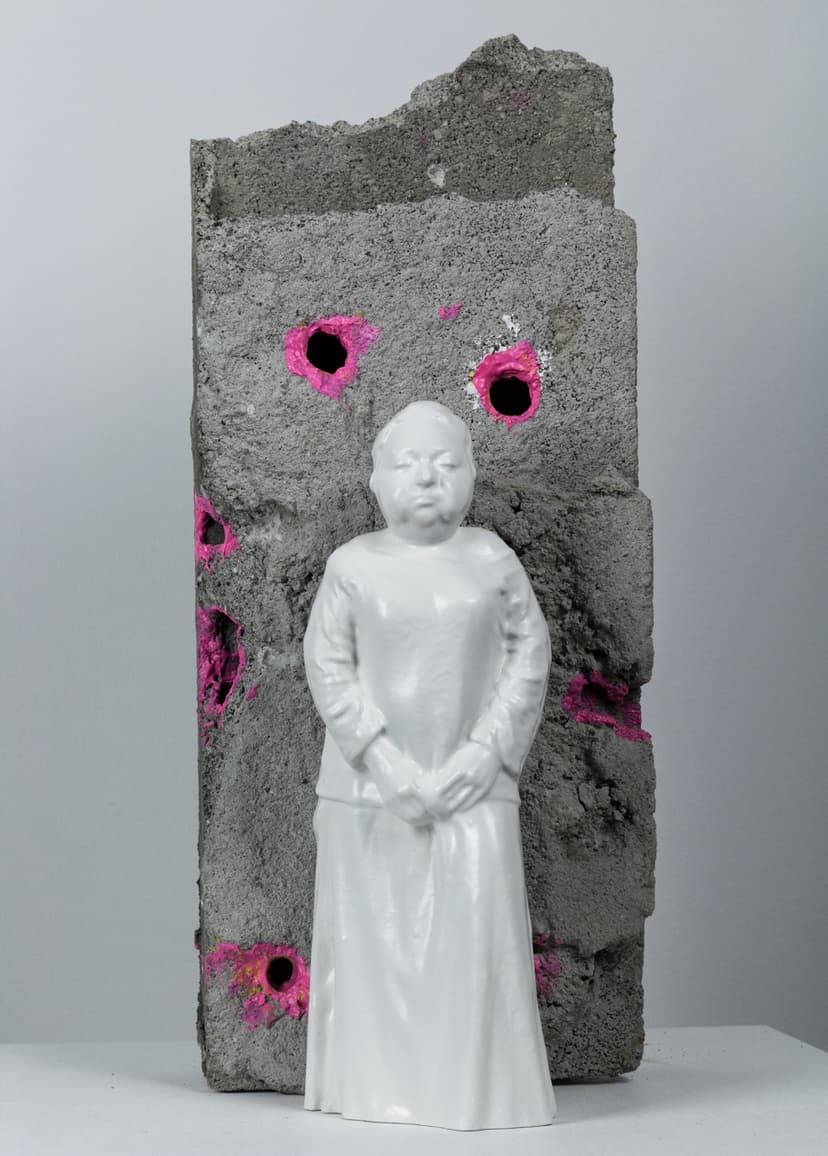 Execution by Federico Clapis, front view: glossy white resin woman in a long dress before a concrete fragment with pink bullet holes