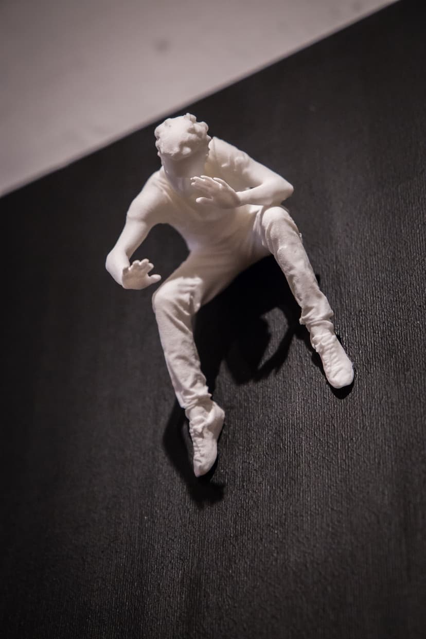 Fear Of Fusion by Federico Clapis: white nylon figure crouching on a black acrylic canvas, shielding his face with one hand