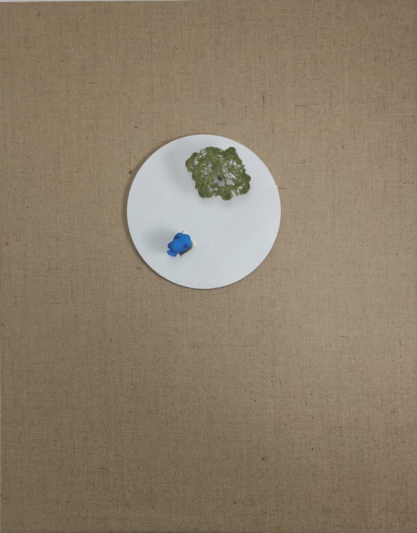 God by Federico Clapis: burlap canvas with a white disc, a small sponge tree and a blue fetus figure seen from above