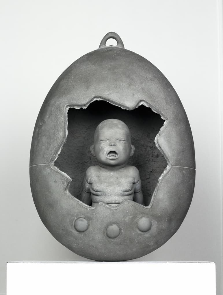 Mamaegotchi by Federico Clapis: grey concrete egg shaped like a Tamagotchi, broken open to reveal a crying newborn inside