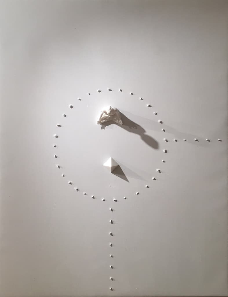 Meditation by Federico Clapis: white canvas with a meditating nylon figure and a pyramid inside a circle of small stones and a dotted line