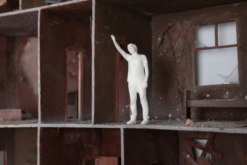 Detail of Memories House by Federico Clapis: the white figure raises an arm in a decayed room with a broken window and boarded walls