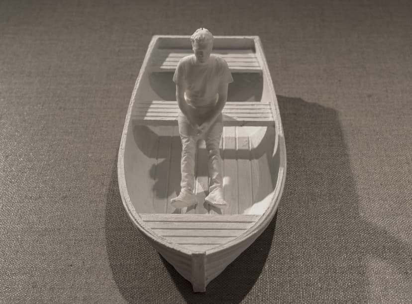Detail of Not Knowing by Federico Clapis: small white figure of a young man sitting in a rowing boat, hands clasped, on grey canvas