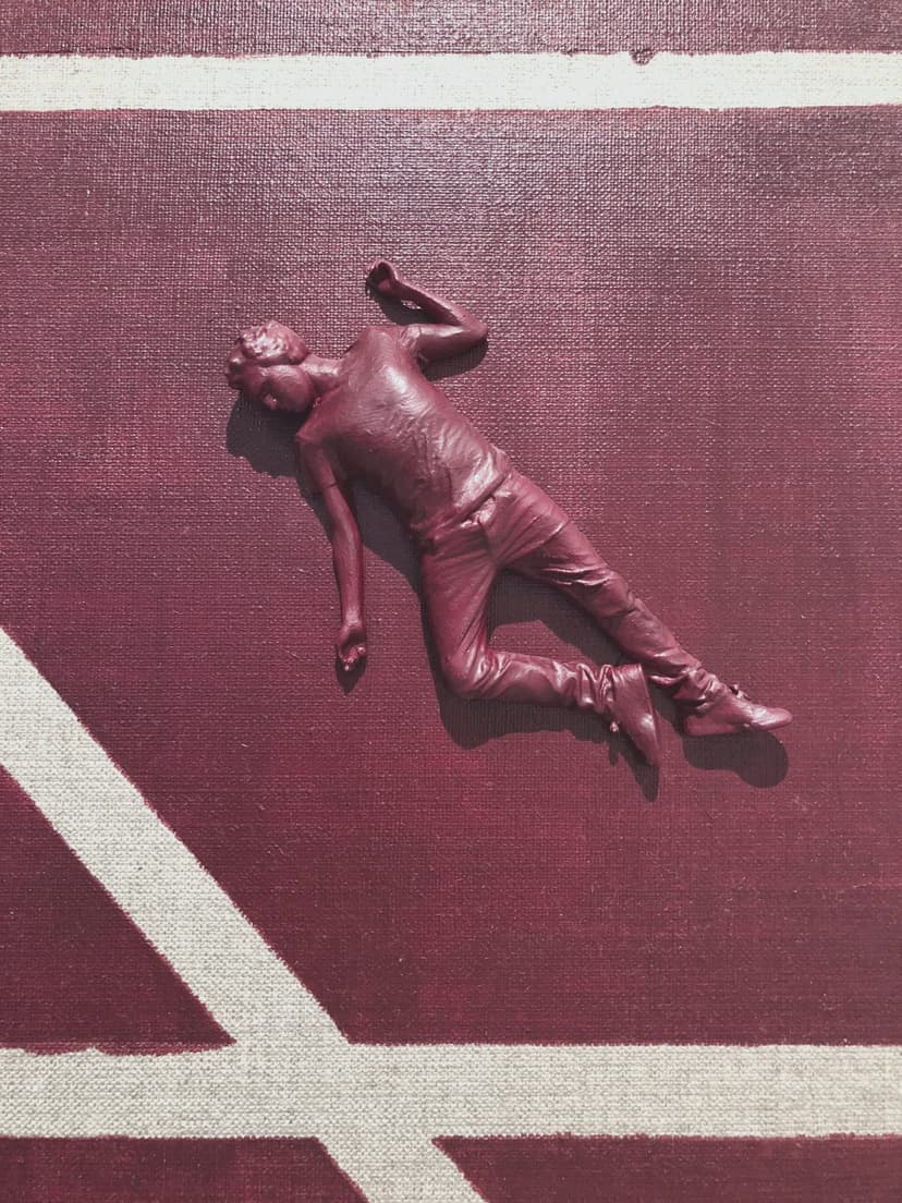 Detail of Personality by Federico Clapis: a dark red nylon powder figure of a young man lying on the painted canvas, arms outstretched