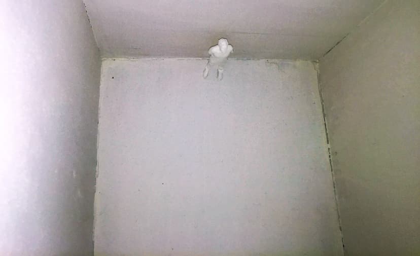Inside Relative Help by Federico Clapis: a tiny white figure stands at the bottom of the empty box, looking up at the walls