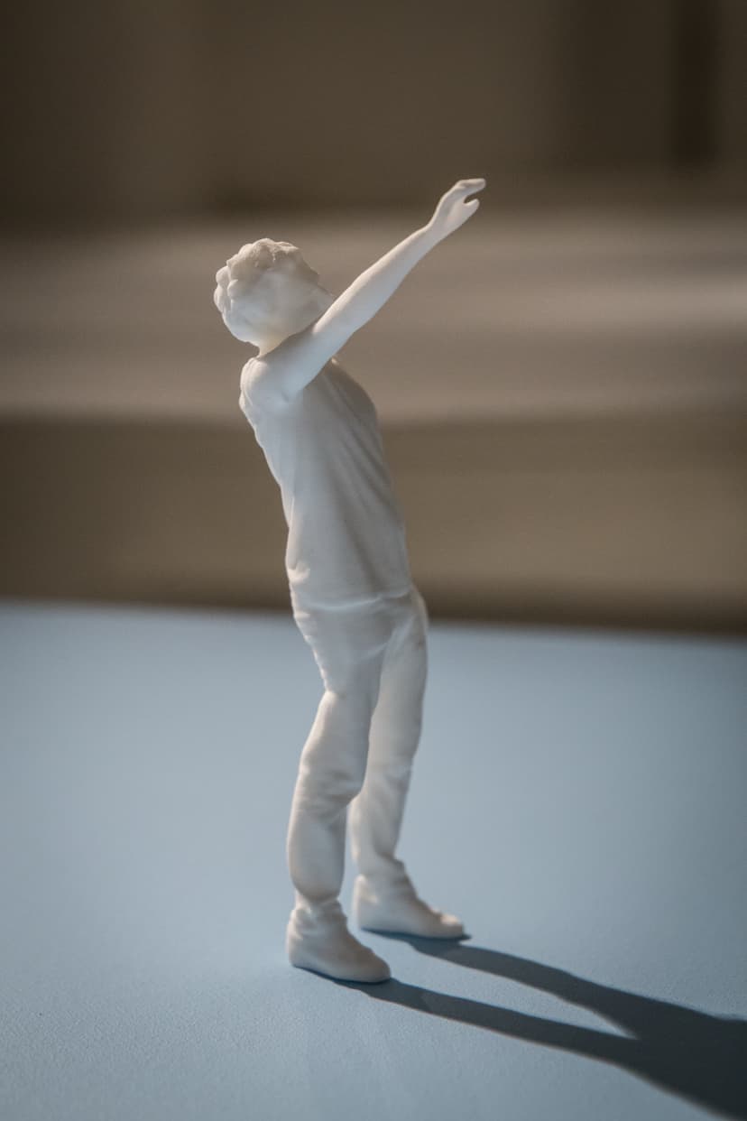 Take Me Away by Federico Clapis: white nylon figure leaning back with one arm raised high, standing on a light blue canvas