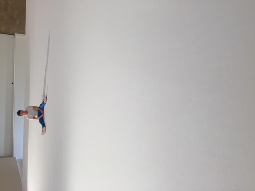 Side view of Federico Clapis's The Immense: tiny seated figure in a white T-shirt and blue jeans at the edge of a large white canvas