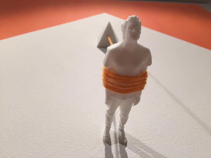 Detail of The Pyramid by Federico Clapis: white figure bound at the waist with orange wool tied to a small white pyramid