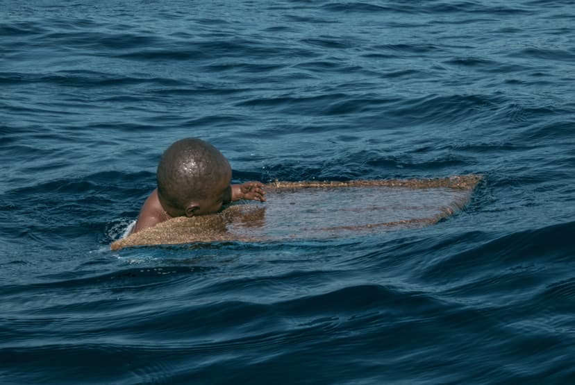 Welcome by Federico Clapis in open water: the baby figure, seen from behind, rests its head on the half-submerged doormat