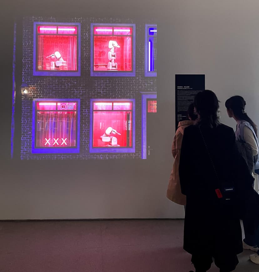 Visitors at CAFA Art Museum in Beijing watch Federico Clapis' projection of robotic arms behind red-lit windows in Crypto Art: A New Possibility