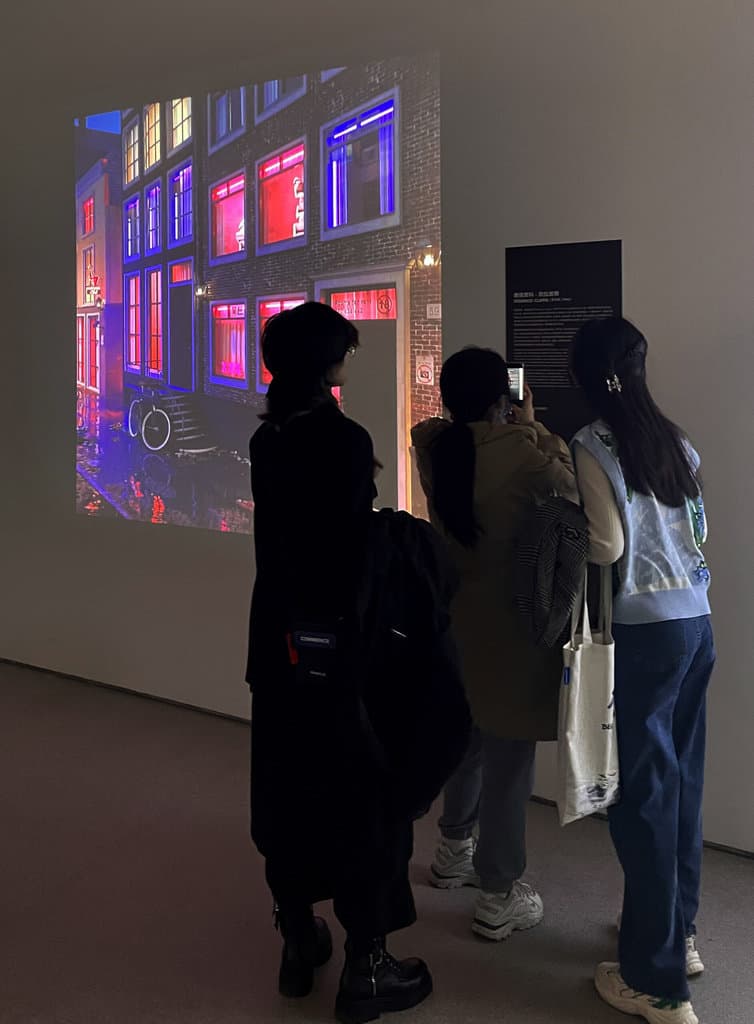 Visitors photograph Federico Clapis' projected night street with red-lit windows at the CAFA Art Museum exhibition Crypto Art: A New Possibility