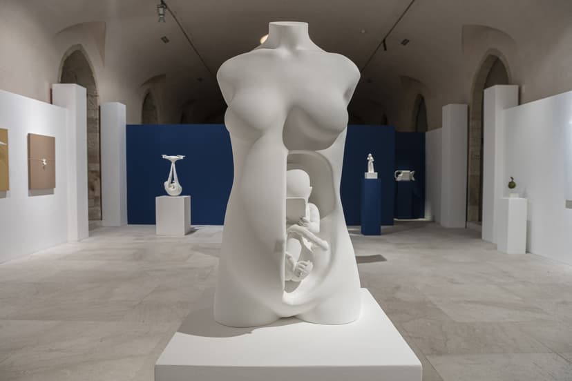 White sculpture of a female torso with a child inside holding a tablet, in the vaulted hall of EXMA during Federico Clapis' Contact Zone