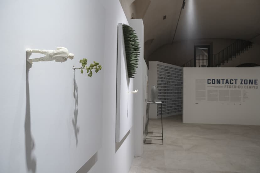 Small white figures emerge from canvases on the walls of Contact Zone at EXMA Cagliari, with the Federico Clapis title wall in the background