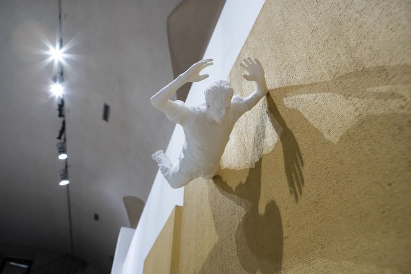 A small white figure climbs out of a jute canvas, lit by gallery spots: an Actor on Canvas work by Federico Clapis at Contact Zone, EXMA