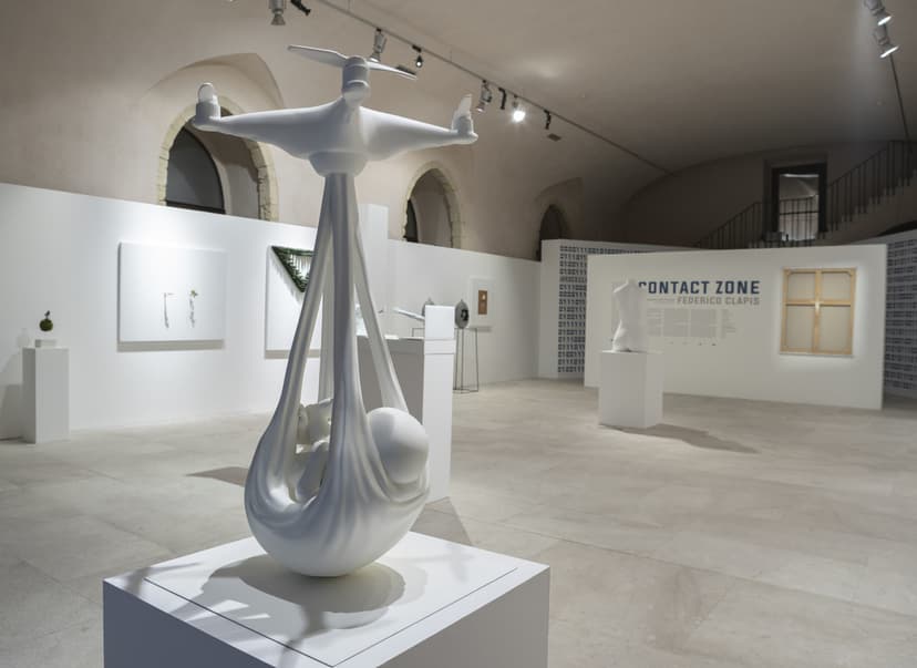 Babydrone by Federico Clapis, a newborn carried in a sling by a drone, in the foreground of the Contact Zone exhibition hall at EXMA Cagliari
