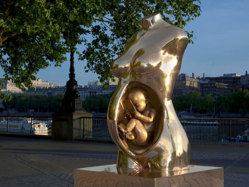 Federico Clapis' bronze Crypto Connection at Observation Point on London's South Bank, a foetus holding a smartphone inside a pregnant torso, Thames behind