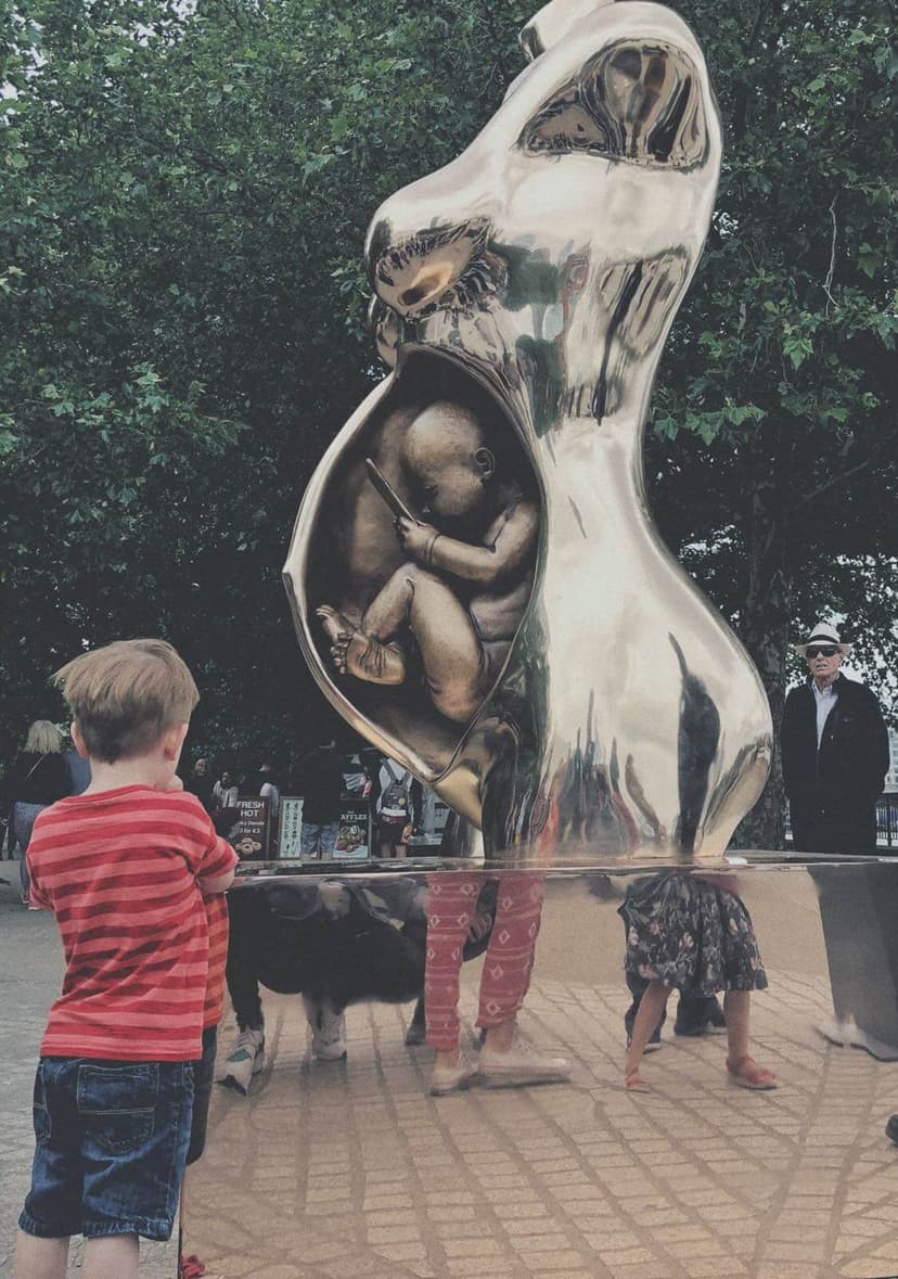 Children and passers-by around Crypto Connection by Federico Clapis on the South Bank in London, the mirror-polished plinth reflecting their legs
