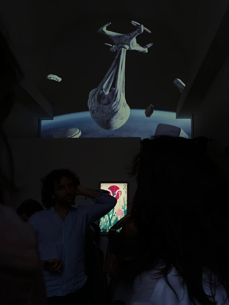 Federico Clapis among visitors at Gea Vision in Bologna, under a video mapping of his Babydrone floating above the Earth in space