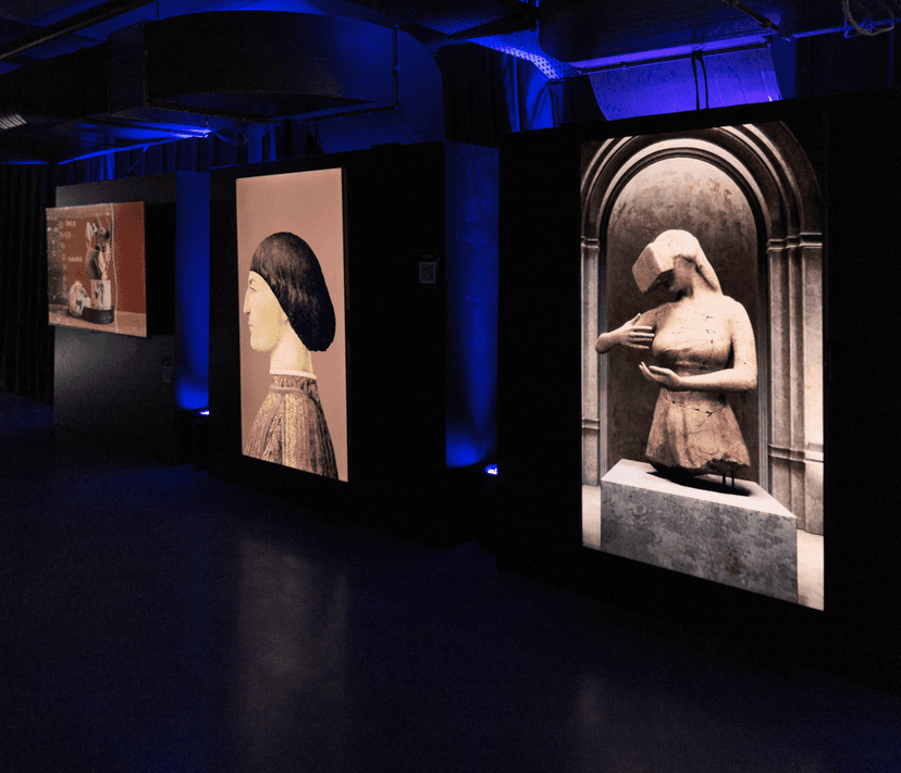 Dark, blue-lit gallery of the İzmir Painting and Sculpture Museum with backlit screens, one showing a digital statue in a VR headset by Federico Clapis