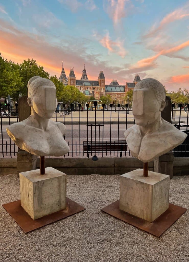 New Race by Federico Clapis, two concrete busts with screen-like slabs over their faces, in the Moco Museum garden facing the Rijksmuseum