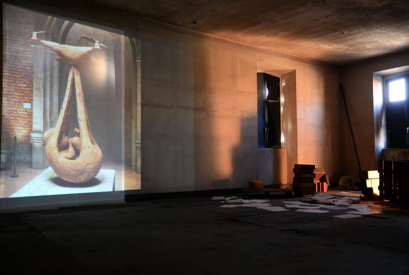 Projection of a terracotta-coloured digital sculpture by Federico Clapis on a bare wall in a dim room of Scalo Vallino during Post-Umano