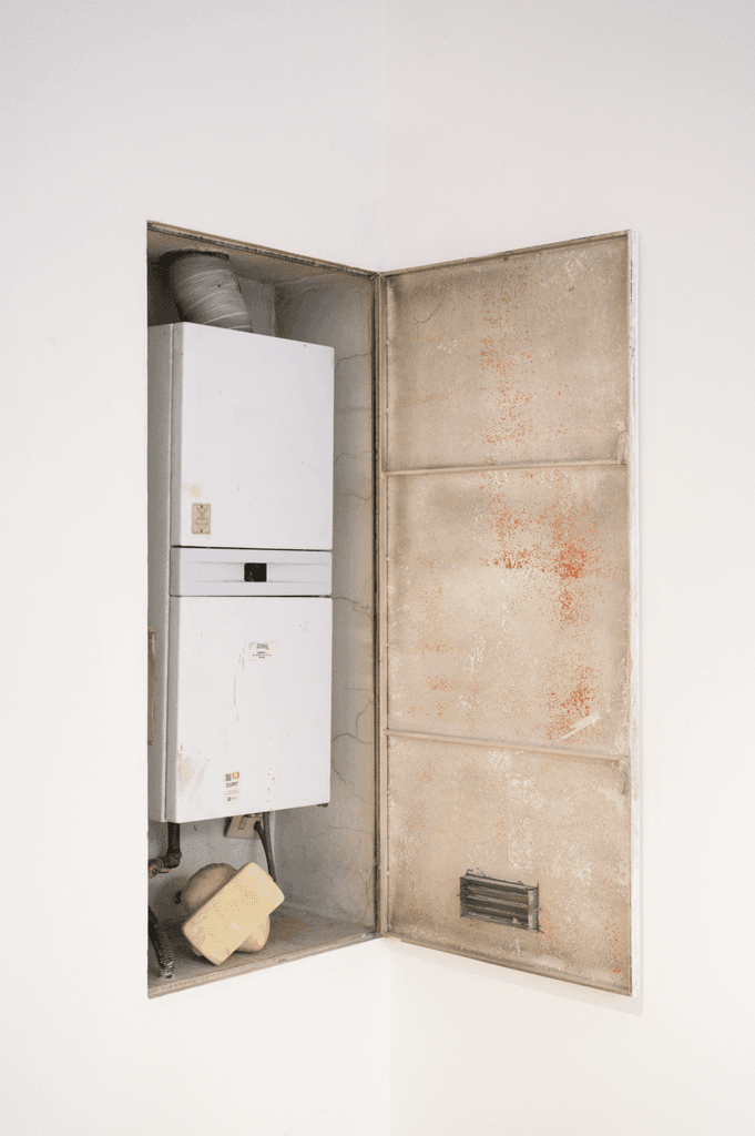 Open wall niche with a boiler and a small pale object inside, part of Spazio mentale = ambiente by Federico Clapis at Bianchi Zardin, Milan