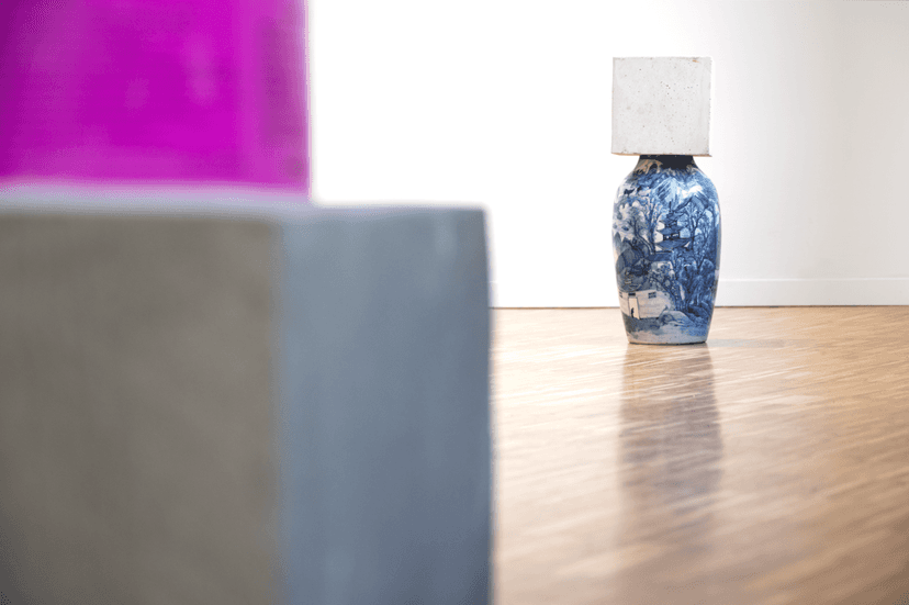 Blue and white porcelain vase topped with a stone block on a parquet floor, in Federico Clapis' exhibition Spazio mentale = ambiente, Milan