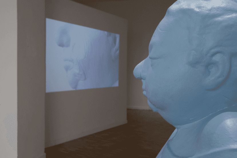 Large pale blue sculpted head in profile before a wall projection of a face, Federico Clapis' Spazio mentale = ambiente at Bianchi Zardin