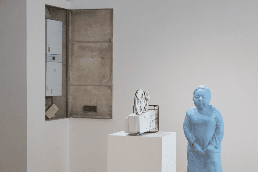Pale blue female figure, white film projector on a plinth and an open boiler niche, installation view of Federico Clapis at Bianchi Zardin