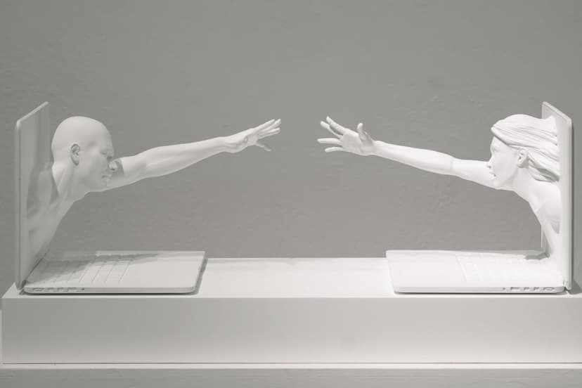 Touch Scream by Federico Clapis at Triennale Milano: two white figures lean out of open laptops, reaching towards each other on a plinth