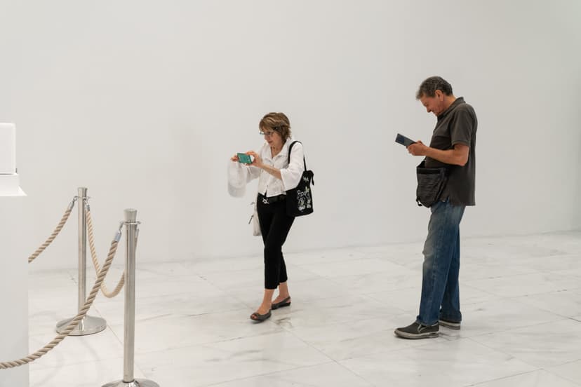 Visitors with phones walk across the marble floor of Triennale Milano near the roped-off plinth of Federico Clapis' Touch Scream